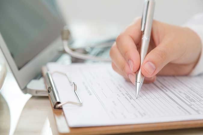 close-up-doctor-filling-out-prescription