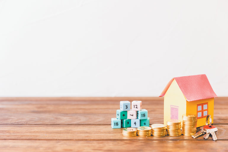 SF_math-blocks-house-key-stacked-coins-wooden-surface-OL