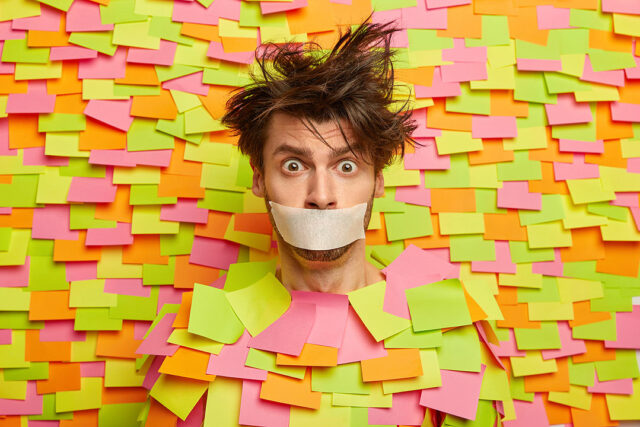 surprised-nervous-man-with-adhesive-duct-tape-mouth-asks-be-silent-stands-silenced-speechless-poses-against-colorful-wall-with-sticky-notes-being-frightened-shut-up-censorship