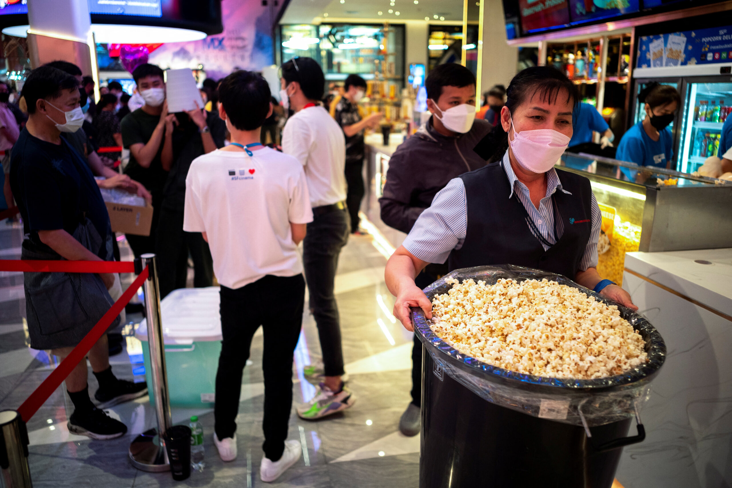 A woman carries a bucket containing popcorn during a campaign "all you can eat popcorn for 199 baht ($5.60)" in front of a cinema inside a department store in Bangkok