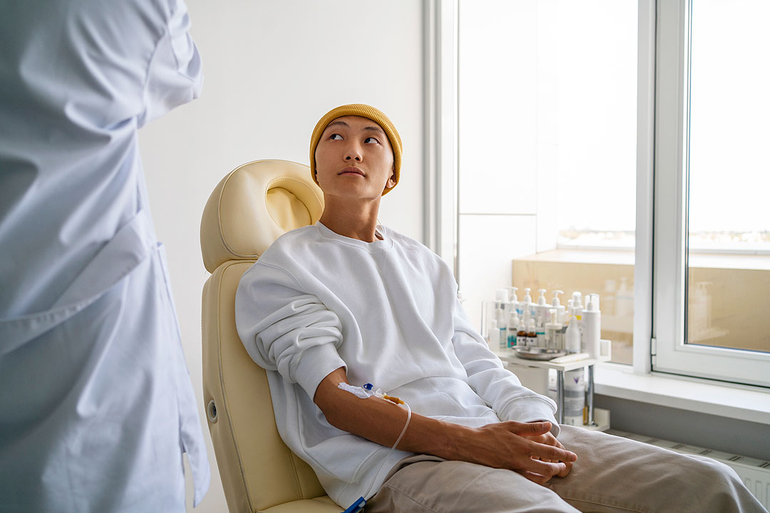 sick-asian-man-sitting-chair-side-view