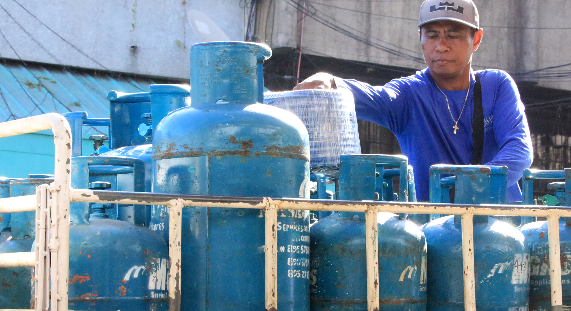 A man arranges tanks of liquefied petroleum gas (LPG) on a truck
