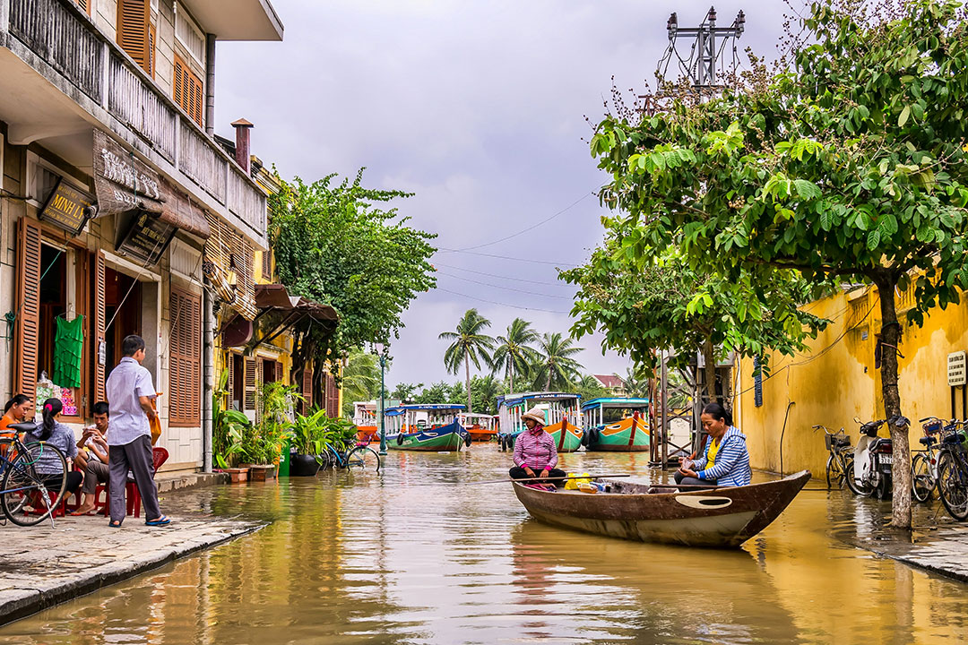 two women riding boat beside brown house