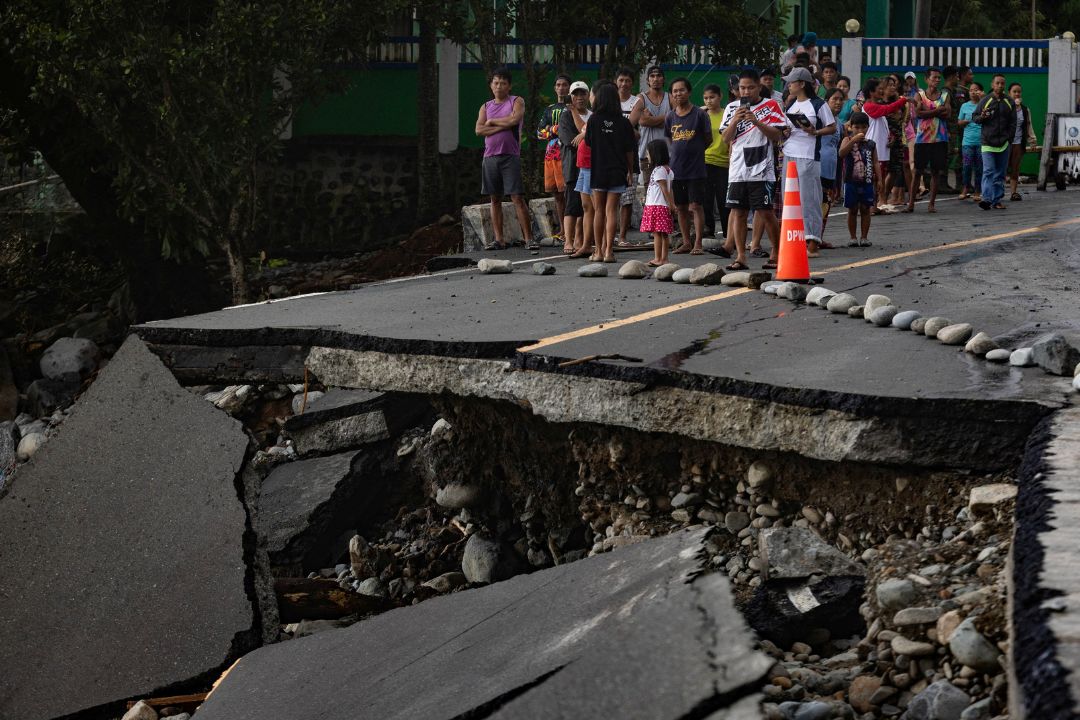 People stand near a wrecked part of the Baler-Casiguran Road